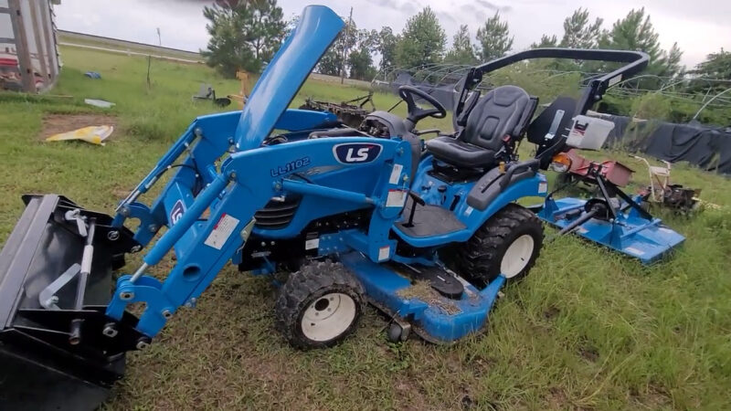 LS MT125 subcompact tractor parked in a field with visible loader attachment and mower deck.